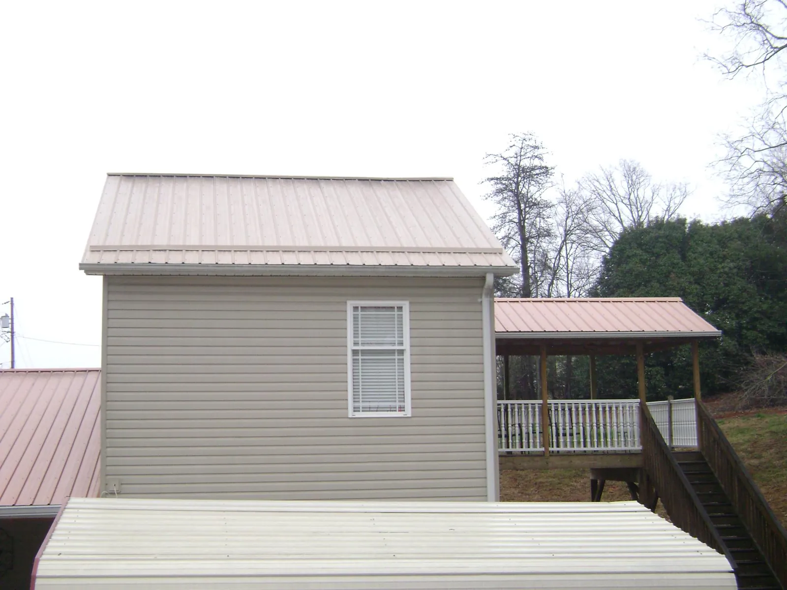 Tan metal roofs on a two story addition and attached porch, from a Roof Replacement job in Whitehouse Station