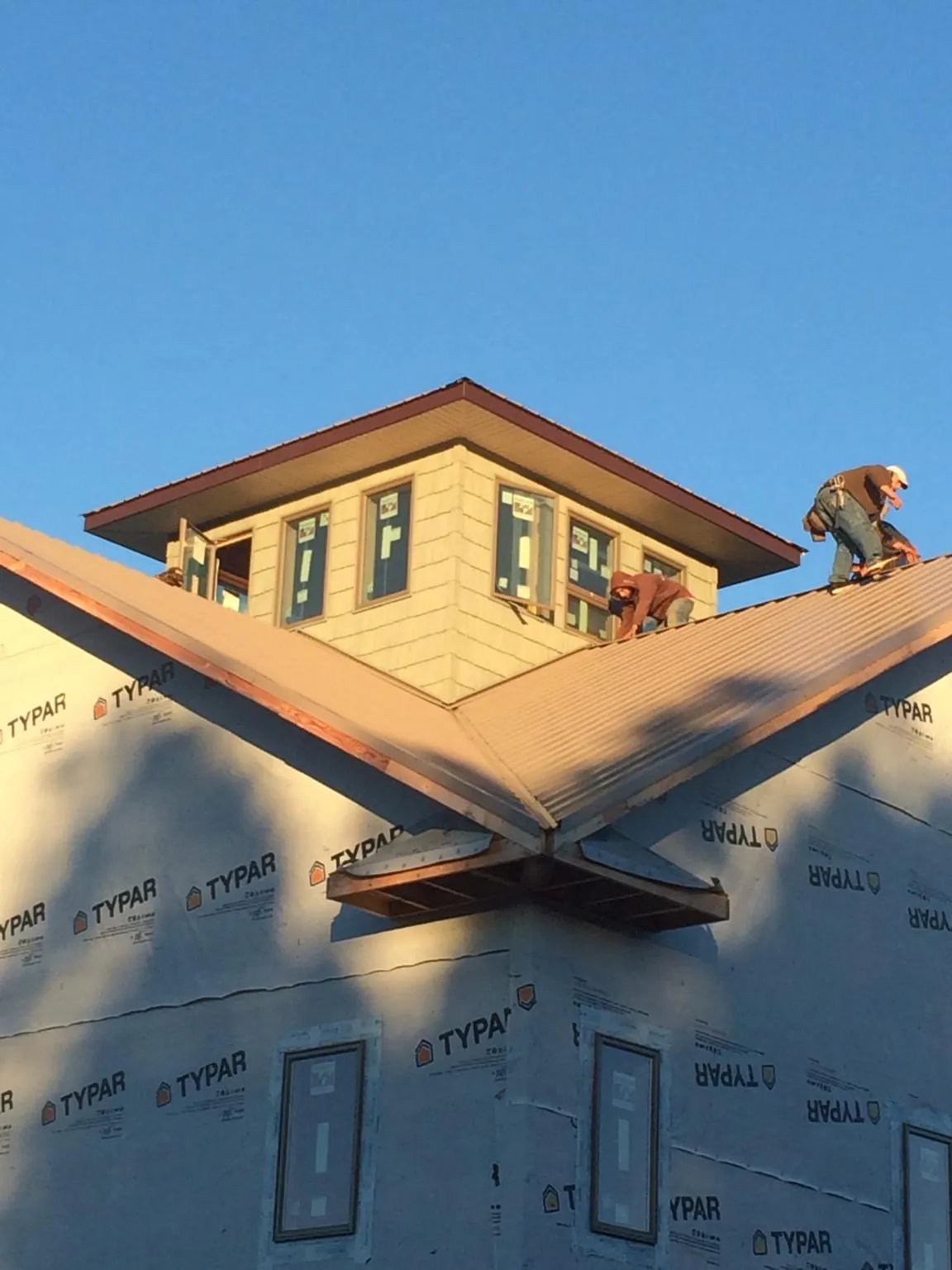 Roofers working around a rooftop cupola on a new metal roof at sunset — Roof Waterproofing in Whitehouse Station by Roofing Brothers